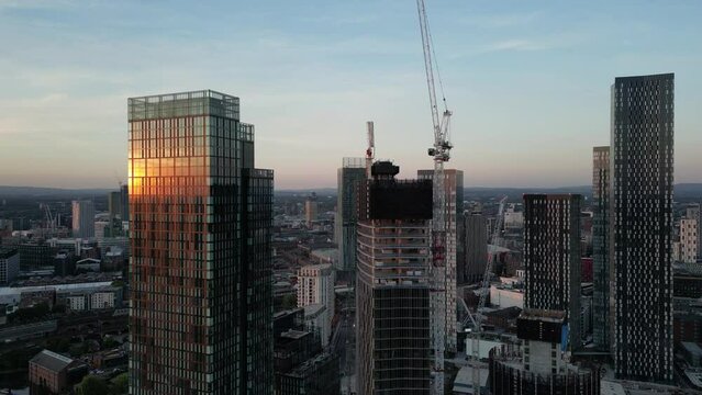 Aerial drone flight in Manchester around Deansgate Towers and new construction of high rises with the sunset in the reflection of the glass