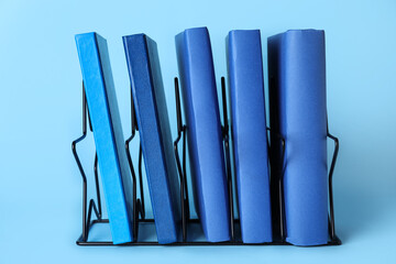 Black metal holder with books on blue background