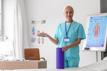 Fototapeta premium Mature physiotherapist with foam roller in rehabilitation center