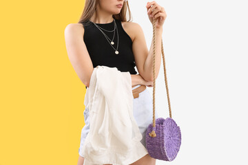 Fashionable woman with stylish rattan handbag on color background