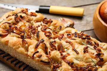 Board of tasty Italian focaccia with onion on table, closeup