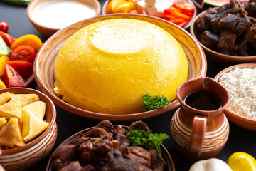 Homemade Romanian Food with polenta, meat, cheese and vegetables. Delicious corn porridge in clay dishes. Mamaliga or polenta, a traditional dish in Moldova, Hungary and Ukrainian cuisine.
