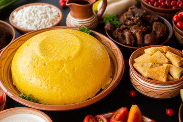 Homemade Romanian Food with polenta, meat, cheese and vegetables. Delicious corn porridge in clay dishes. Mamaliga or polenta, a traditional dish in Moldova, Hungary and Ukrainian cuisine.

