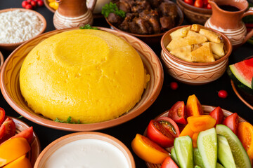 Homemade Romanian Food with polenta, meat, cheese and vegetables. Delicious corn porridge in clay dishes. Mamaliga or polenta, a traditional dish in Moldova, Hungary and Ukrainian cuisine.
