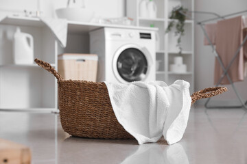 Wicker basket with clean towel in laundry room, closeup