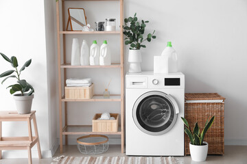 Interior of light laundry room with washing machine, shelving unit and houseplants