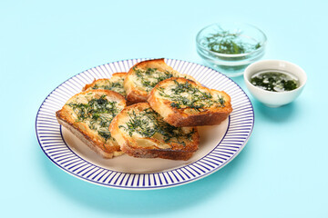 Plate with slices of toasted garlic bread on color background