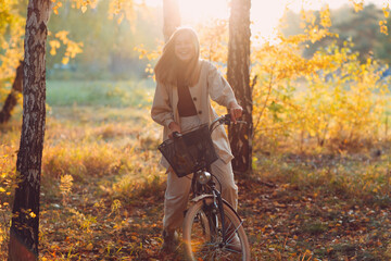Happy active young woman riding vintage bicycle in autumn park at sunset.