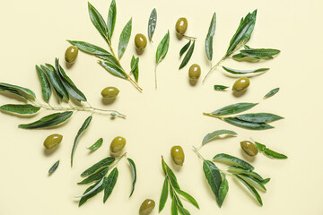 Frame made of green olives and leaves on beige background