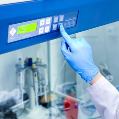A researcher is turning on the safety laminar flow cabinet in a cell culture laboratory in order to...