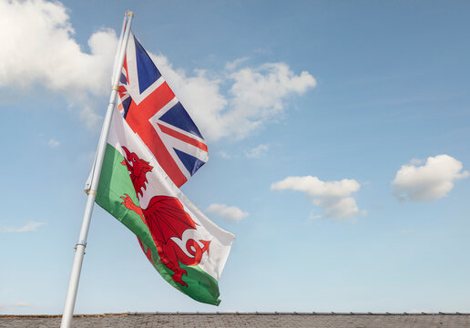 The British Union Jack and the Welsh flag fly proudly togetheragainst a blue summer sky