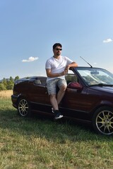 Man leaning against convertible classic car,