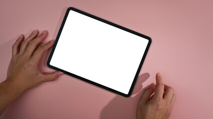 Overhead view man hands using digital tablet on pink background. Empty screen for your advertise text