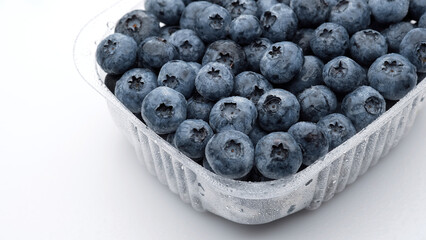 Fresh blueberries in container for delivery or sale, isolated on white background