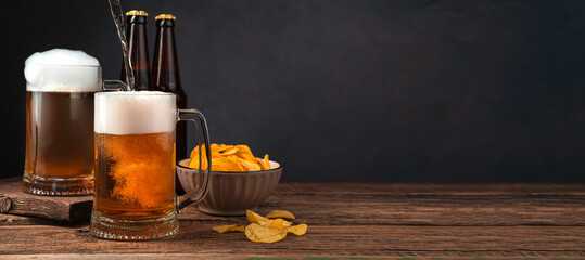 Cold beer in two glasses and a bowl of potato chips on a dark background. The name of the beer....