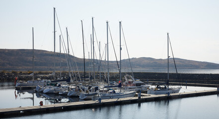 Fototapeta na wymiar A bright and calm March morning, sailing yachts and other craft moored in the Portavadie Marina on Loch Fyne on the west coast of Scotland