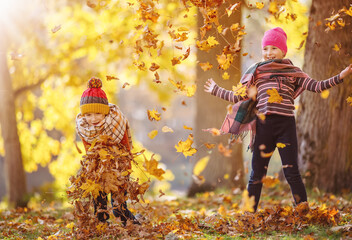 Children throwing colourful leaves in autumnal park
