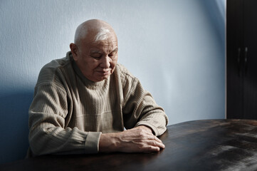 Fototapeta premium Pensive and thoughtful senior man sitting at the table