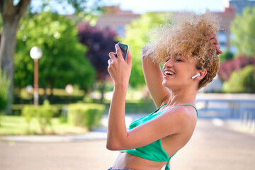 Portrait of young Brazilian woman wearing earphones listening music and laughing in a summer day.