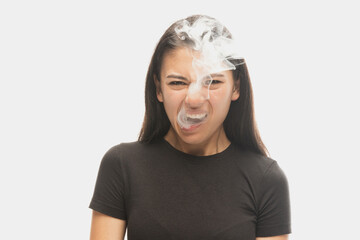 Angry young girl with dark hair releases smoke from the mouth isolated over white background....