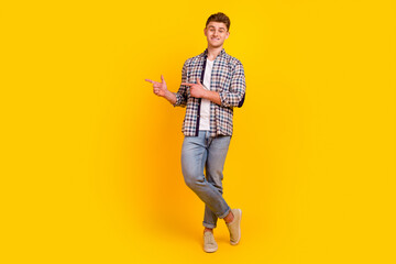 Full size photo of young cheerful man indicate fingers empty space promo isolated over yellow color...