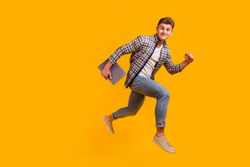 Fototapeta na wymiar Full body profile side photo of young man jumper runnner rush hold laptop isolated over yellow color background