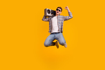 Full length photo of young man jumper active hold boombox sound melody isolated over yellow color...