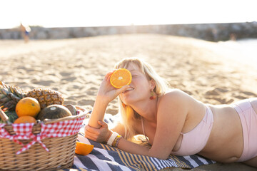  Cheerful young woman enjoy at tropical sand beach. Girl eating a fruit