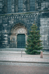 Christmas tree decorated with lights placed outside the entrance to Lund cathedral