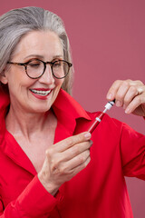 Woman in red bright shirt holding lip gloss and looking contented