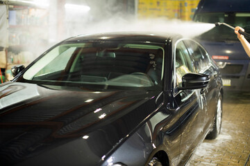 Car wash. Black car in car wash. Hot water jet.