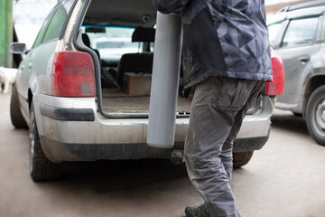 Man puts gas cylinder in trunk of car. Dangerous cargo in transport.