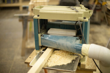 Cutting board in wood workshop. Processing of wood bar. Sawing off layer. - obrazy, fototapety, plakaty