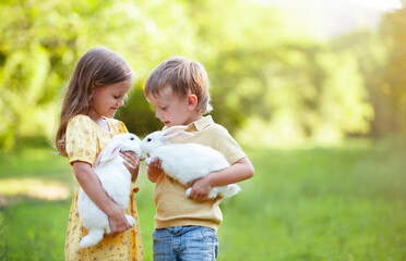 a little boy and a girl are holding rabbits in their arms and introducing them to each other