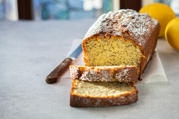 Sliced lemon cake with poppy seeds on a gray background. Copy space.