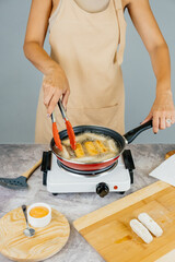 Latin american cook preparing and frying venezuelan tequeños, latin appetizer