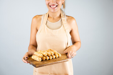 Latin girl holding a wooden board with freshly cooked tequeños, typical Venezuelan food