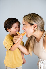 Mother and son enjoying and eating a Latin American snack called tequeños, funny expressions on their faces