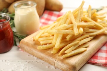 Delicious french fries served on white wooden table, closeup