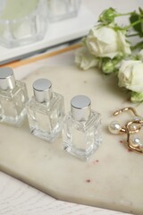 Perfumes and stylish earrings on white table