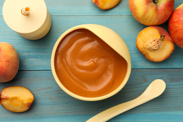 Bowl of tasty pureed baby food and ingredients on light blue wooden table, flat lay