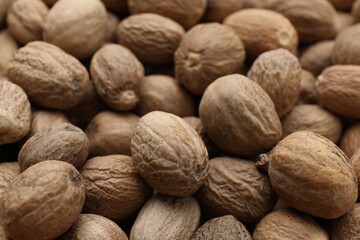 Heap of nutmeg seeds as background, closeup