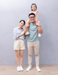 Young Asian family standing on background