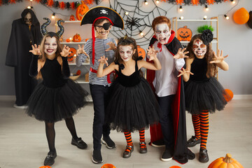 Portrait of group of children in creative costumes with scared faces at Halloween party. Little...