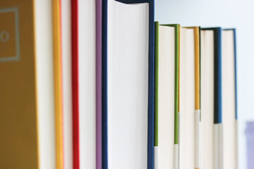 A stack of modern red, yellow, blue, violet books in bright hardcovers stacked on a bookshelf....