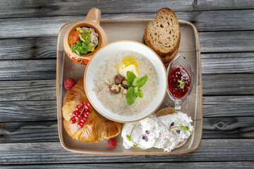 Breakfast. Fruits, croissants, porridge, poached eggs. On rustic dark wooden table.