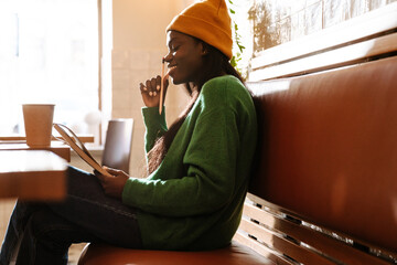 Young beautiful long-haired thoughtful african woman in yellow winter hat