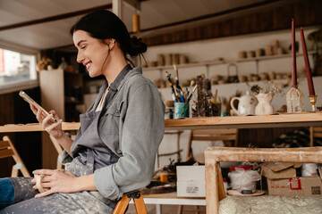 Young beautiful smiling woman in apron sitting on chair