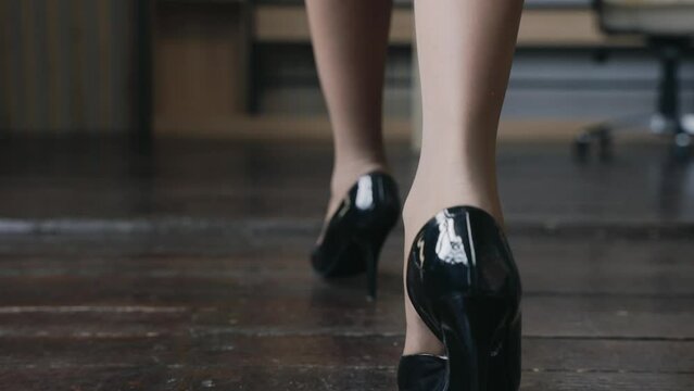 Cinematic close up shot of business woman walking in black heels in the office, slow motion.