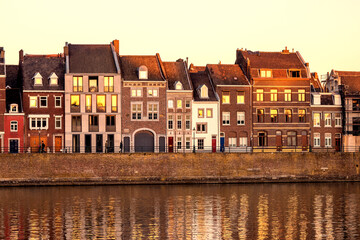 View of a beautiful sunset on the waterfront of Maastricht, the Netherlands, where the old town houses are reflected in the river Maas